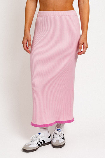 woman wearing a pink ribbed midi skirt with a contrasting hem and paired with white and black sneakers