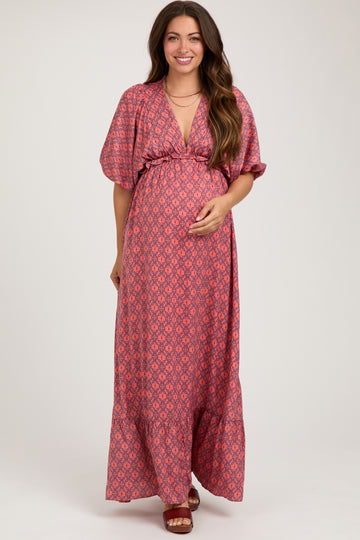 woman wearing a pink patterned short sleeve maternity maxi dress and holding her baby bump