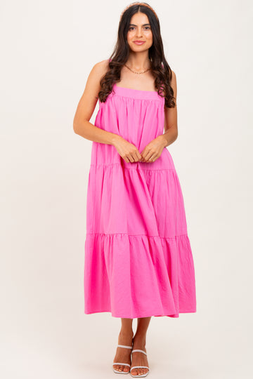 woman wearing a vibrant pink tiered maxi dress with a strapless design and a flowy silhouette