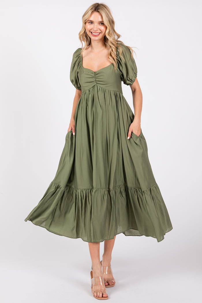 woman wearing a green puff sleeve maxi dress with a tie front and side pockets