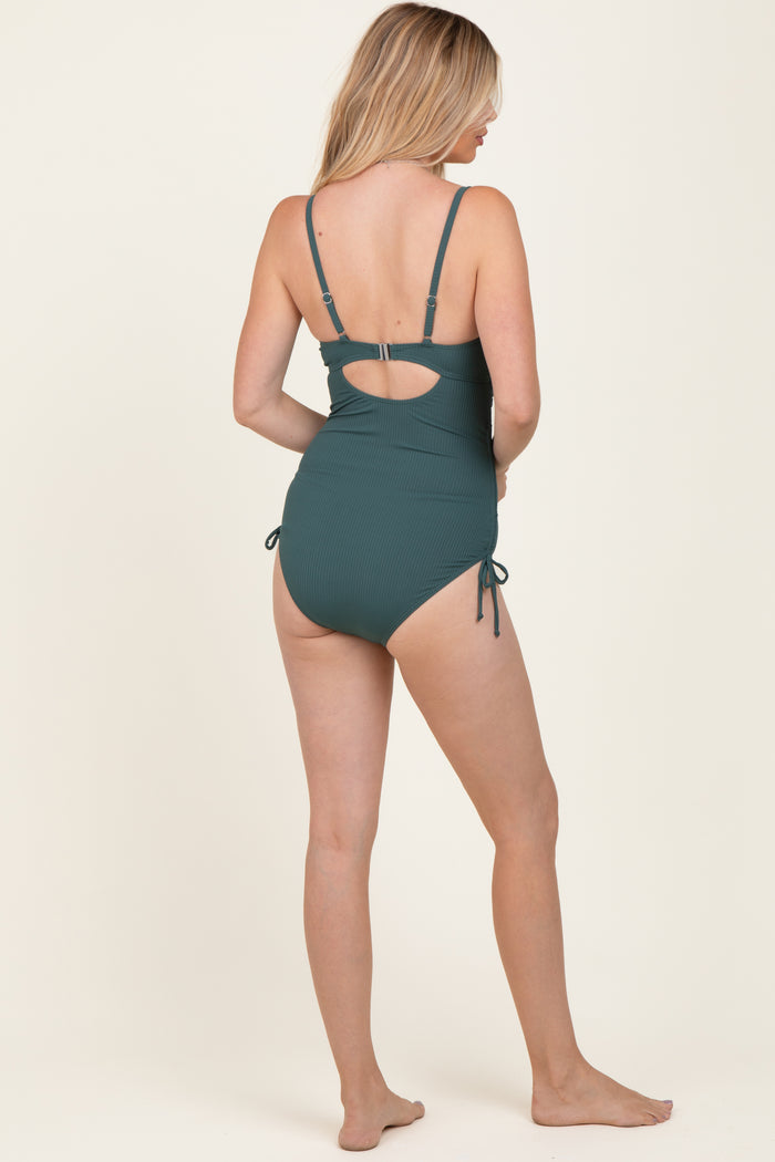 woman wearing a dark green striped one-piece swimsuit with a back cutout and adjustable side ties
