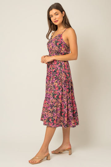 woman wearing a pink and purple floral midi dress with thin straps and a flared skirt