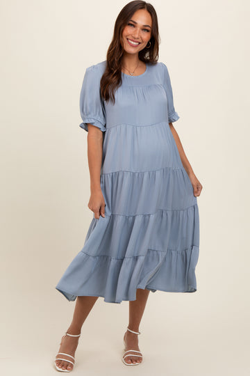 woman wearing a light blue tiered maternity dress with short puff sleeves and a flowing skirt, baby bump visible