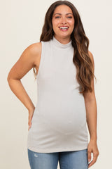 woman wearing a light gray ribbed sleeveless maternity top and showing her baby bump