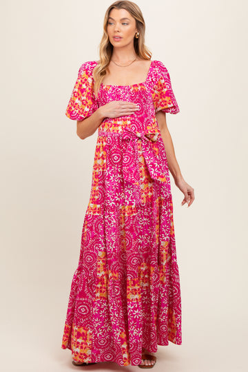 woman wearing a pink floral maternity maxi dress and holding her baby bump
