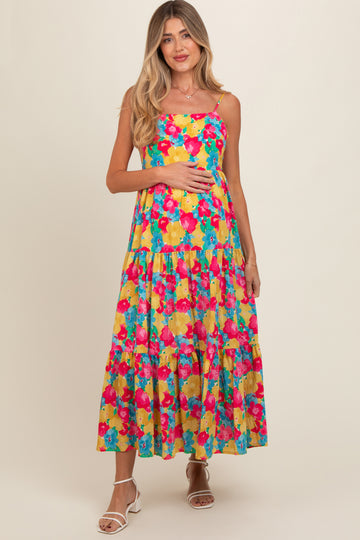 woman wearing a colorful floral maternity maxi dress with a tiered skirt and holding her baby bump