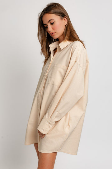 woman wearing an oversized beige button-up shirt with a single pocket and relaxed fit