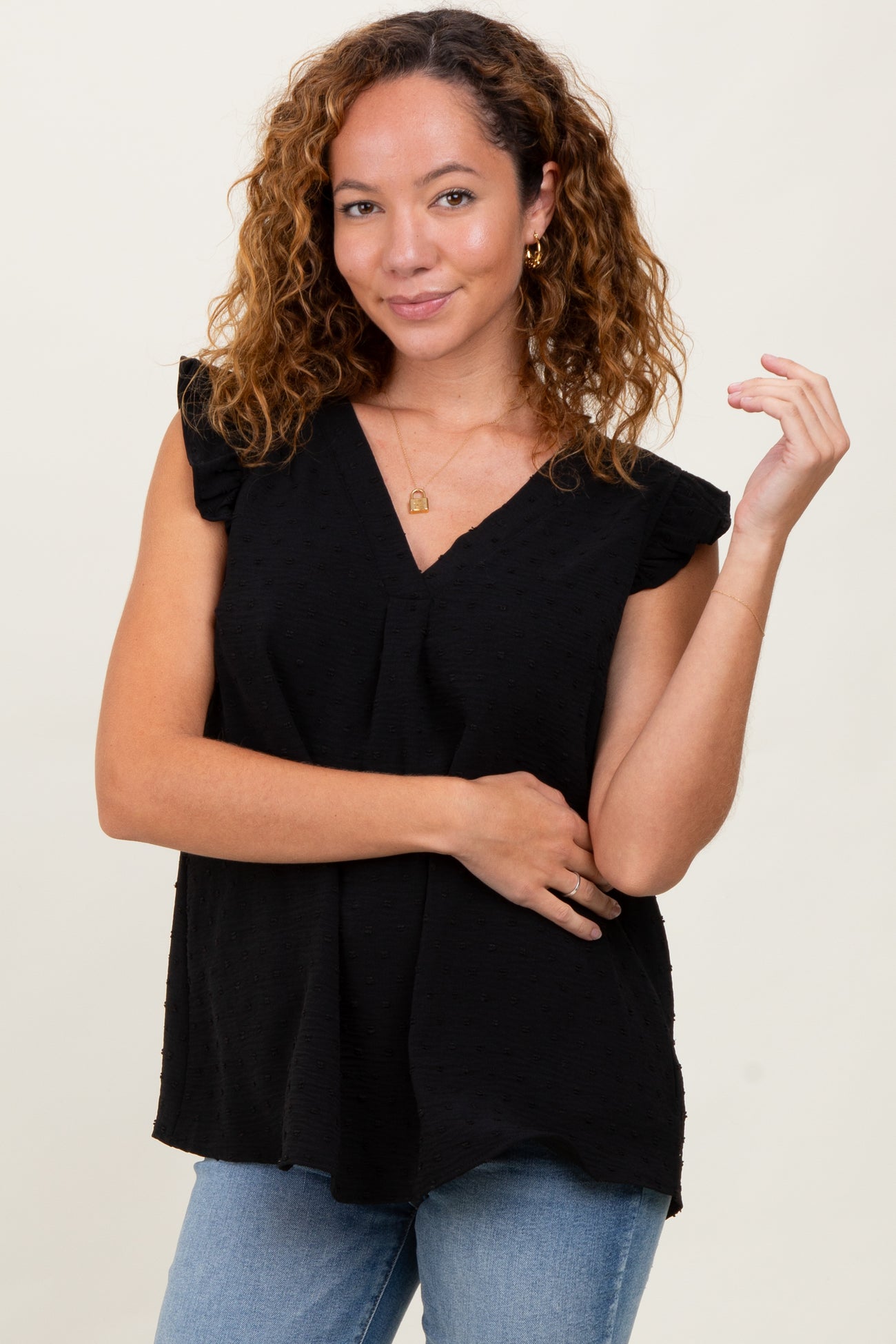 woman wearing a black short sleeve top with ruffle details, styled with light blue jeans