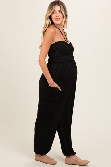 woman wearing a black strapless maternity jumpsuit with pockets and a visible baby bump