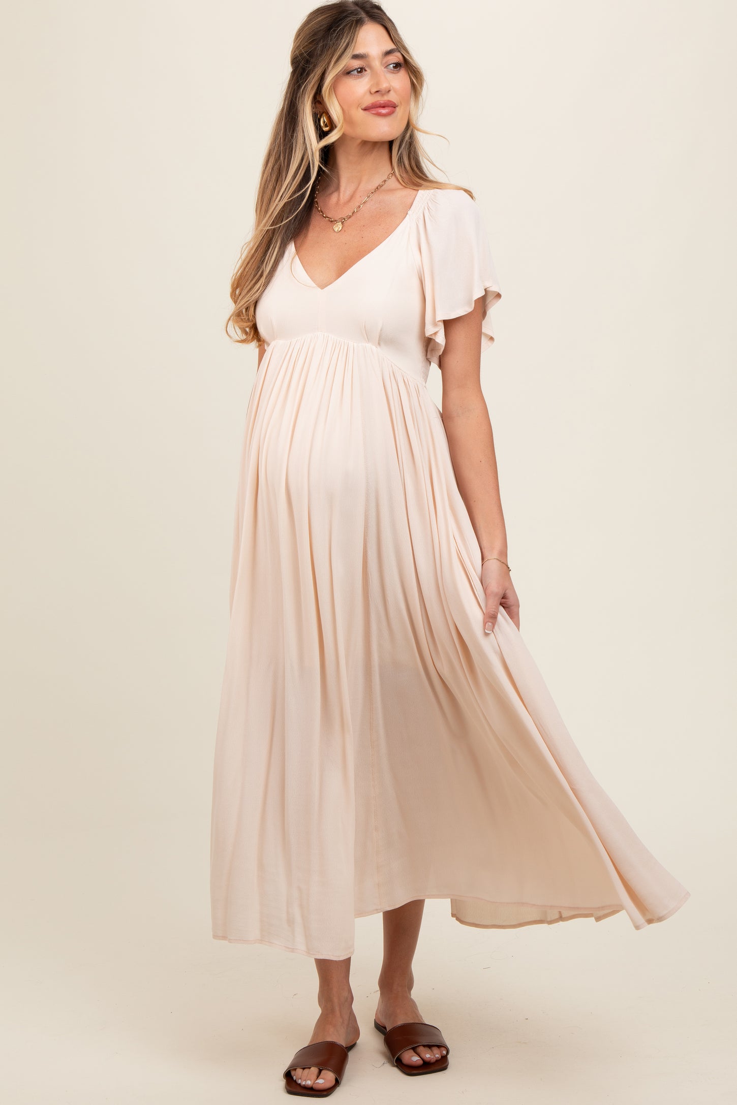 woman wearing a blush pink short sleeve maternity dress with a flowy skirt and a visible baby bump