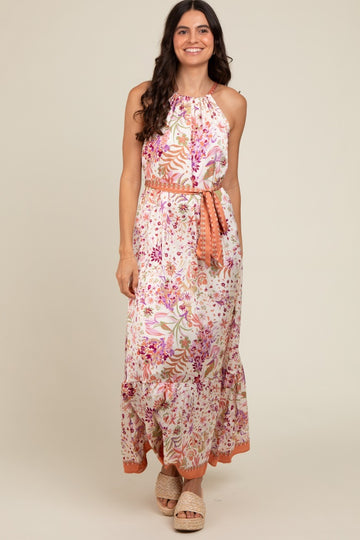 woman wearing a floral maxi dress with a halter neckline and side tie, featuring pink and orange accents