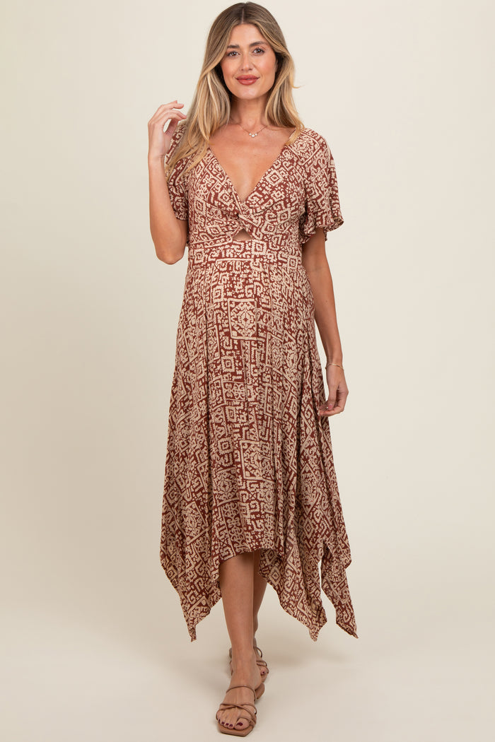 woman wearing a patterned brown maternity dress with a v-neckline and flutter sleeves, showing her baby bump