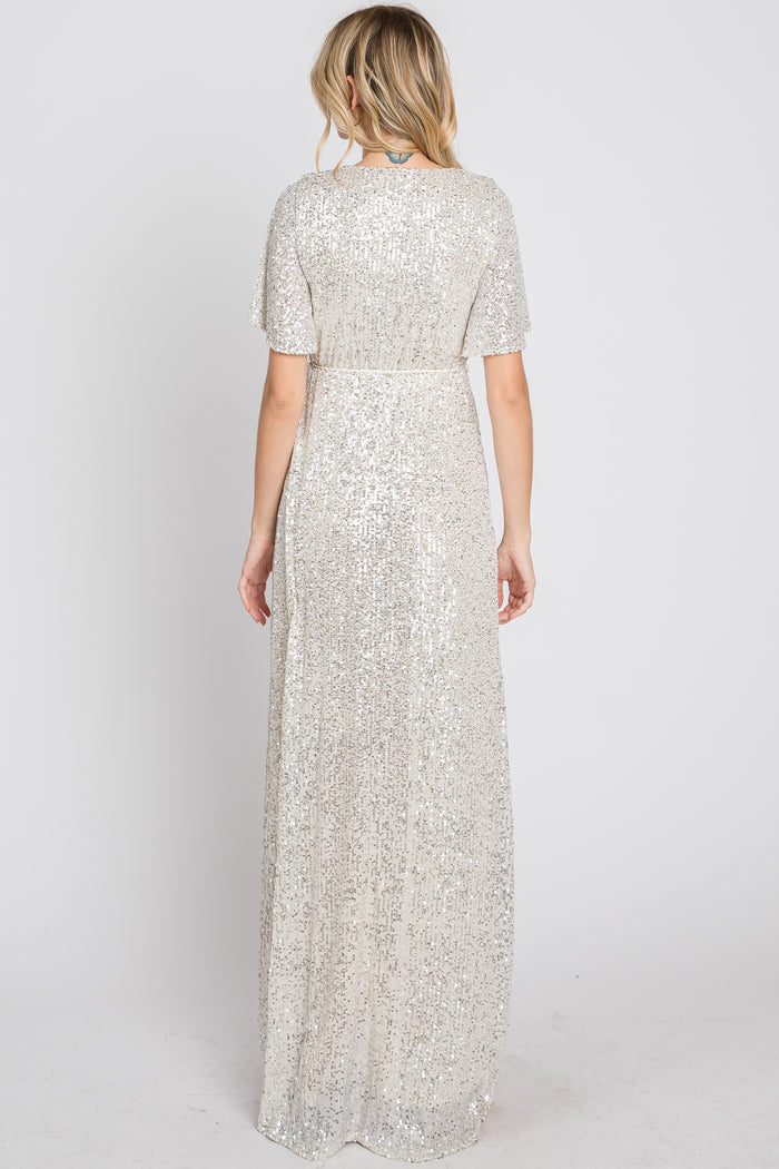 woman wearing a shimmer silver sequin long evening dress with short sleeves and a fitted waist, seen from the back