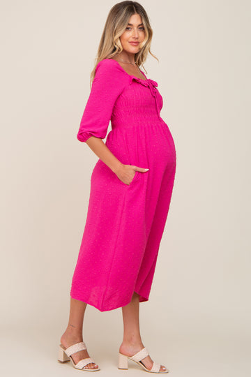 woman wearing a hot pink maternity dress with a tie detail and pockets, showing a baby bump