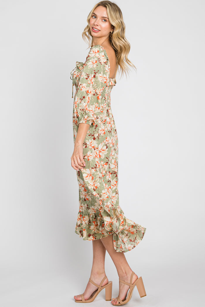 woman wearing a green floral midi dress with puff sleeves and a ruffled hem, standing sideways with a smile