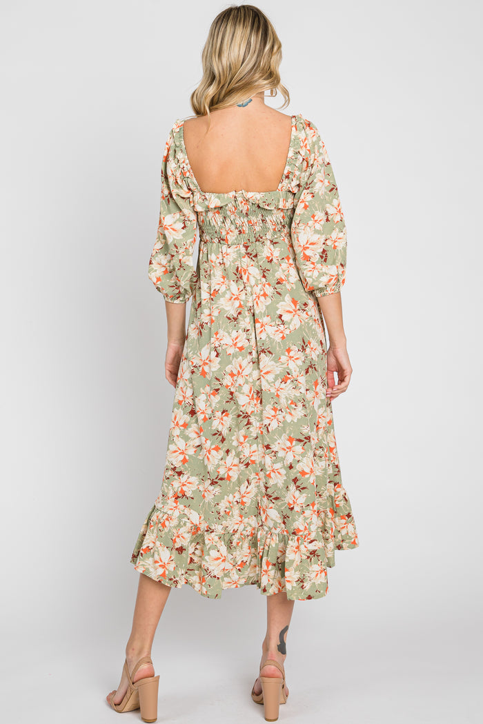 woman wearing a green floral midi dress with puff sleeves and a ruffled hem, showing a bare back