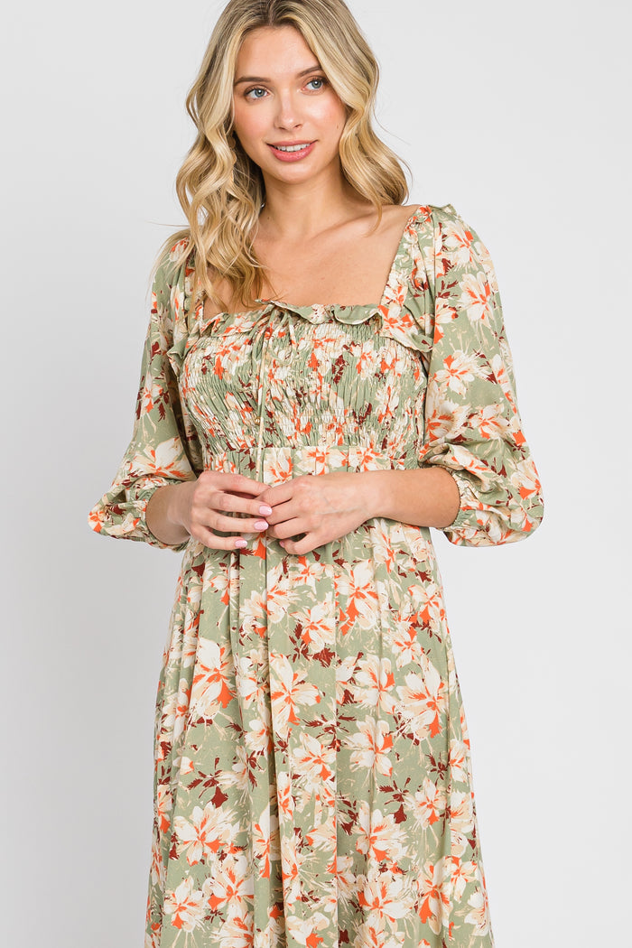 woman wearing a green floral midi dress with puff sleeves and a smocked bodice