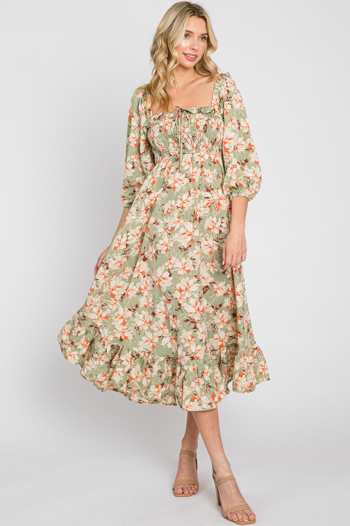 woman wearing a floral midi dress in green with puff sleeves and a ruffled hem, styled with beige sandals