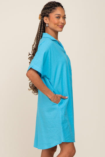Woman wearing a bright blue short-sleeve linen shirt dress with her hand in the pocket