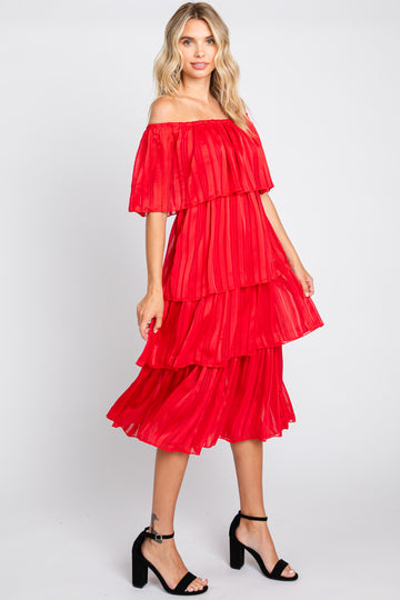 woman wearing a red off-the-shoulder tiered dress with a flowing silhouette and black block-heel sandals