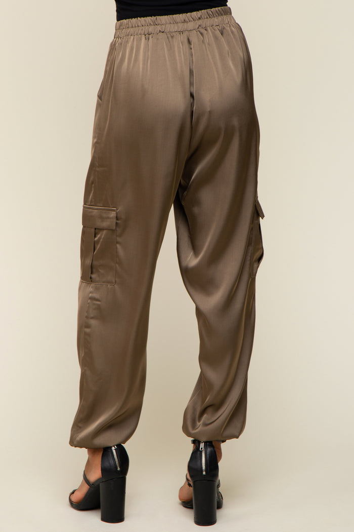 Back view of olive green satin cargo pants with elastic waistband and side pockets paired with black heels