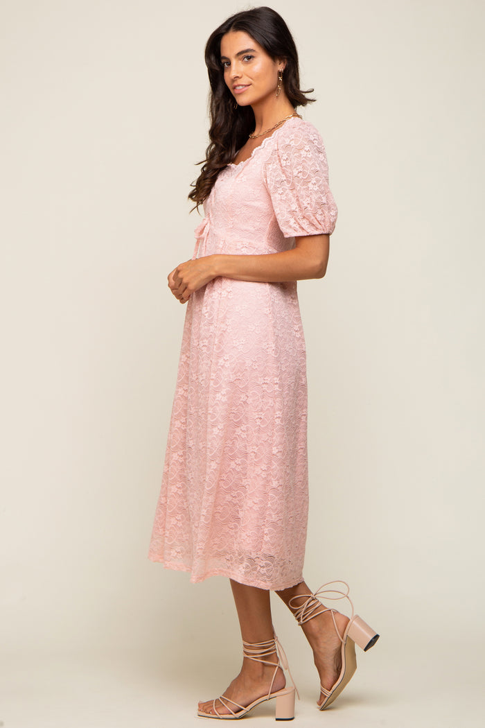 woman wearing a light pink lace midi dress with puff sleeves and strappy block heel sandals