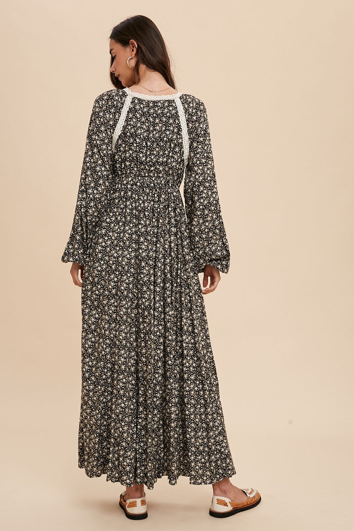 woman from behind wearing a long sleeve black floral maxi dress with white lace trim and puff sleeves