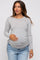 woman wearing a grey striped long sleeve maternity top with side ruching and holding her baby bump