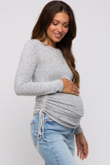 woman wearing a gray striped maternity long sleeve top and holding her baby bump