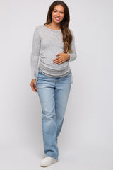 woman wearing a light gray striped long sleeve maternity top with side ruching and blue jeans, showcasing her baby bump