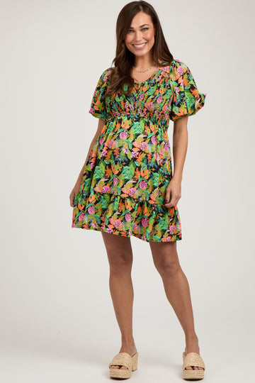 woman wearing a colorful floral maternity dress with ruffled sleeves and a tiered skirt, showing her baby bump